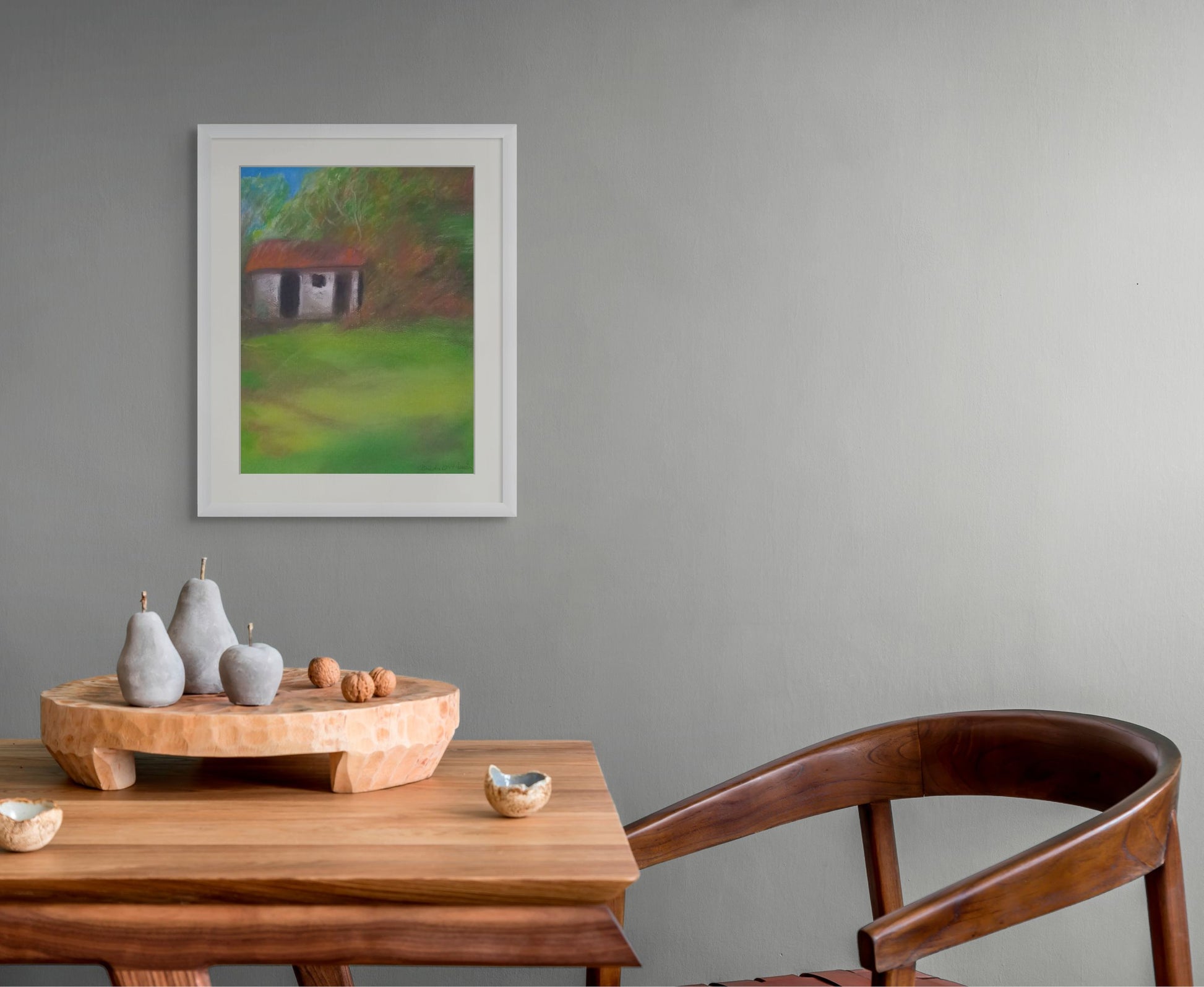 Wooden table with decorative items and a chair, framed painting on the wall.